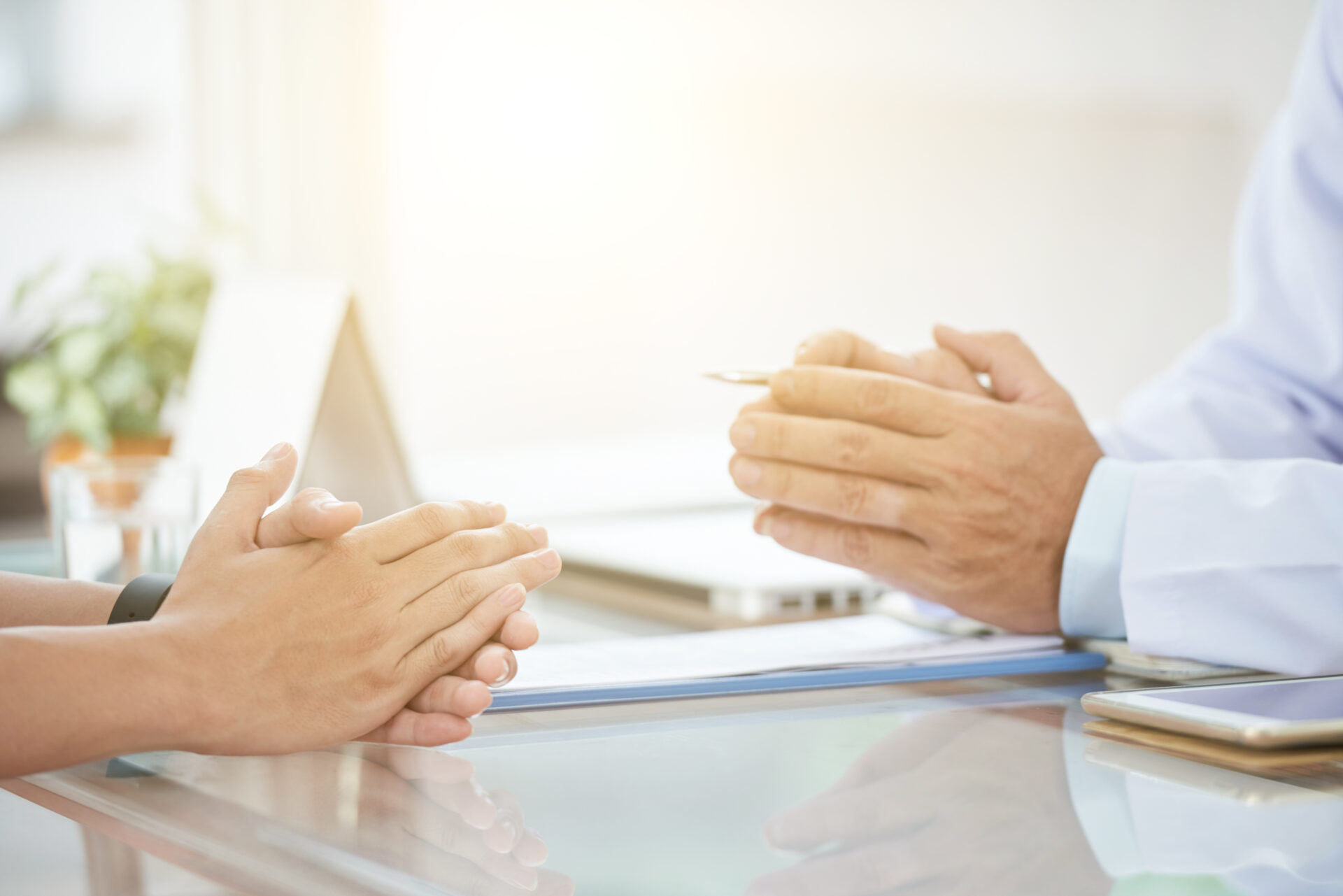 A doctor is shaking hands with a patient at a desk, discussing insurance.