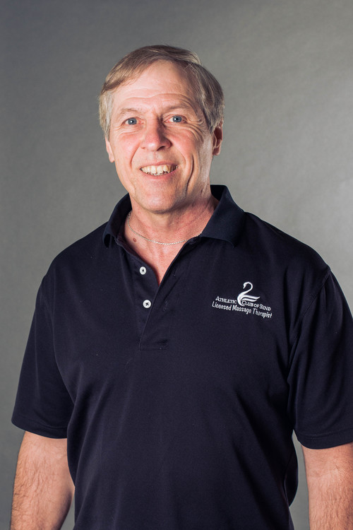 A man in a black polo shirt smiles for the camera.