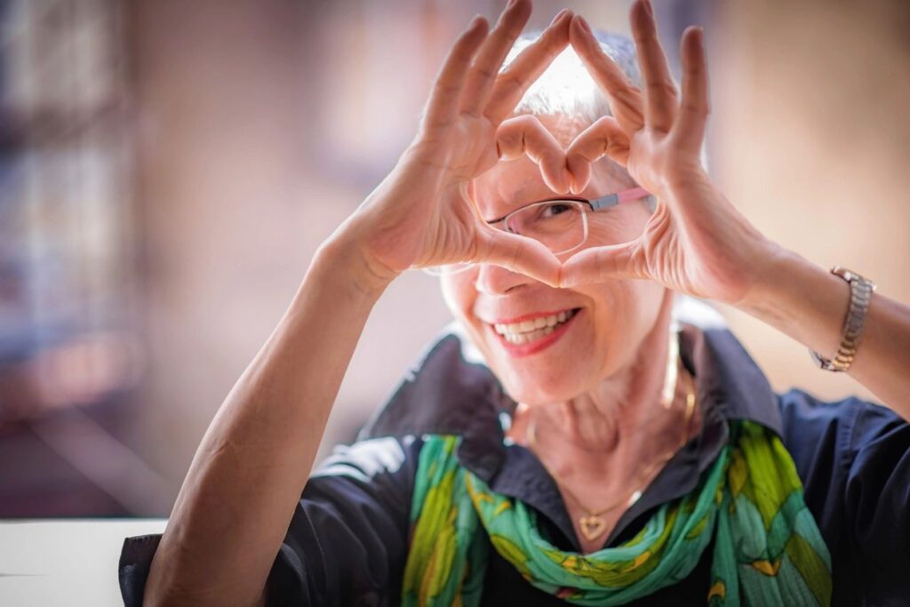 A woman is walking and making a heart shape with her hands.